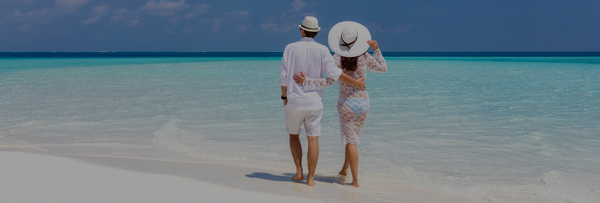 man and woman walking on beach in all white