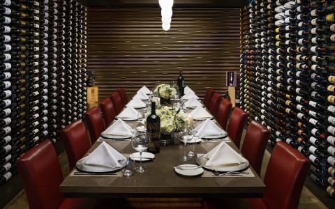 private dining table set with 12 seats and bottle wines hangin up on the wall