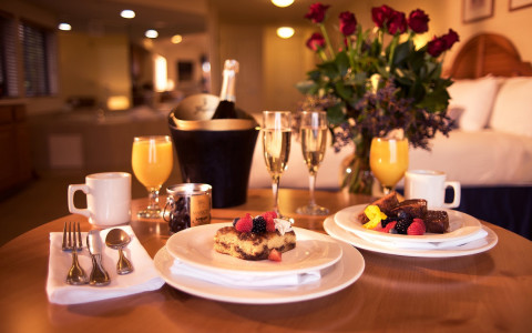 In room meal set for two with roses and bottle of champagne