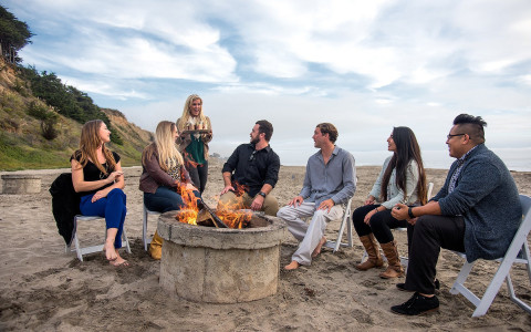 Group of people gathered around fire pit on the sand