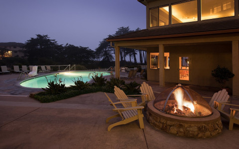 Chairs around fire pit next to pool 