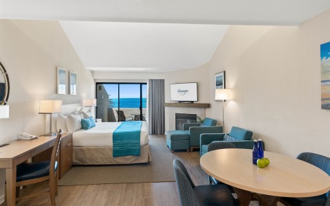 ocean front suite with bed dining table and blue chairs