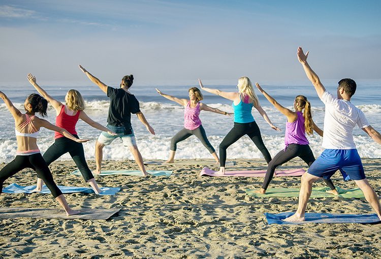 Group of people doing yoga next to the beach