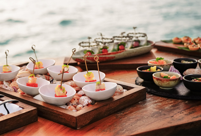 plated appetizers on individual plates on a wooden table in front of the ocean
