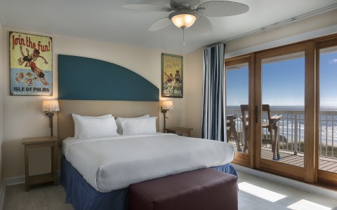 king guest room with bed, tv and balcony overlooking ocean