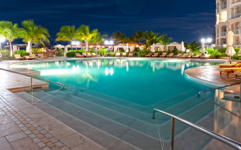 night time view of pool with lounge chairs