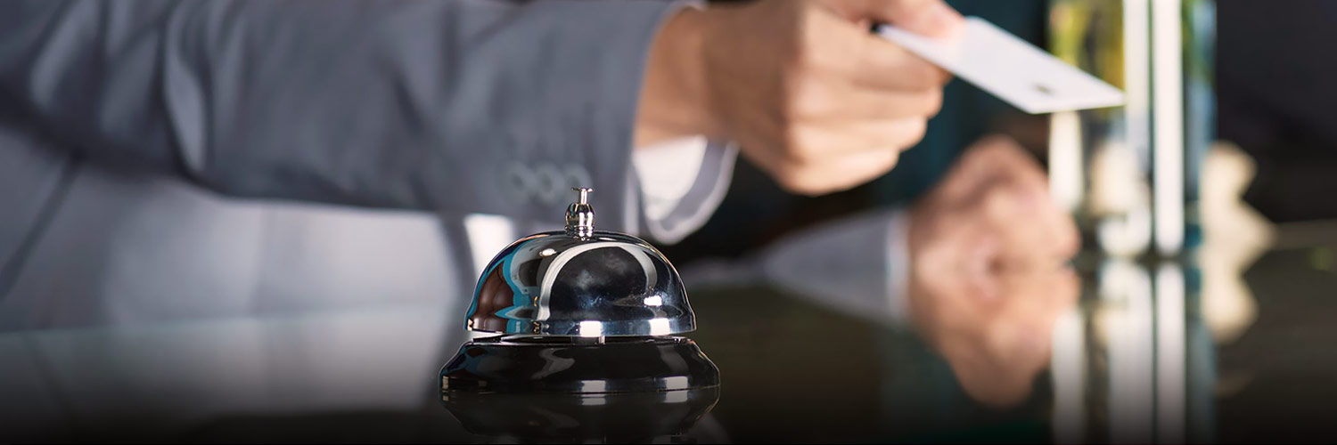 Hand with room key card and concierge bell