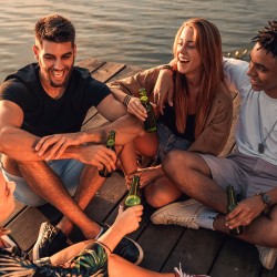 friends toasting beers during golden hour on a dock