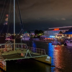 nighttime view of the river with boats parked at docks and a lively nightlife around