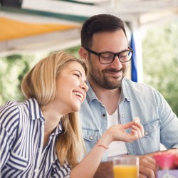 a couple laughing while enjoying a meal on a shaded patio