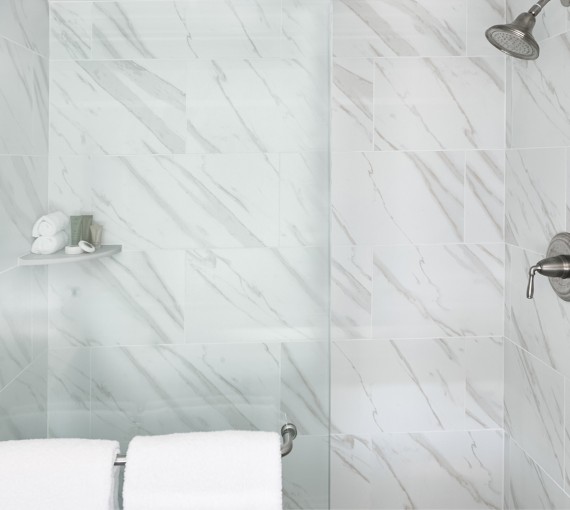 walk-in shower with a glass door with white linen towels