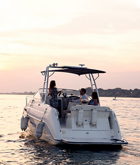 three people enjoying themselves on a boat as the sun goes down in the background