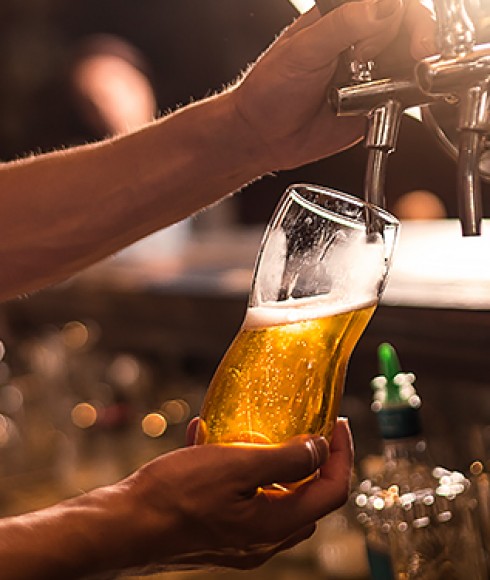 a person pouring a glass of beer from the tap
