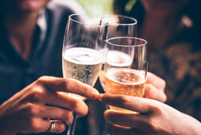 A close up of three people holding their glasses of champagne together for a cheers