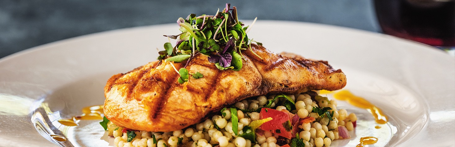 Grilled salmon over a bed of pearl couscous garnished with greens