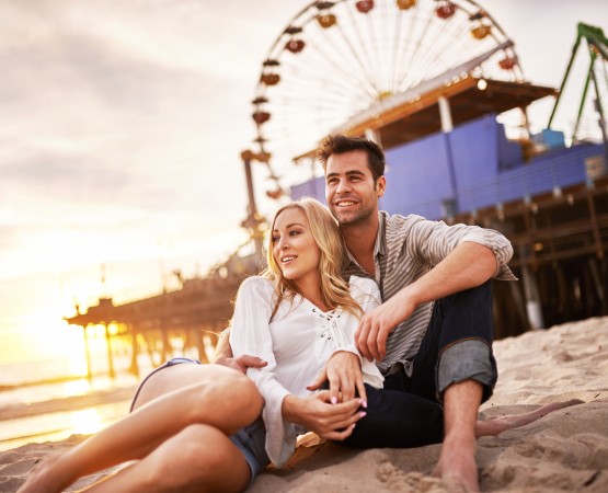 couple embracing in front of santa monica pier 