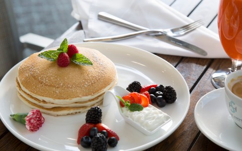 stacked fluffy pancakes with whipped cream and fruits