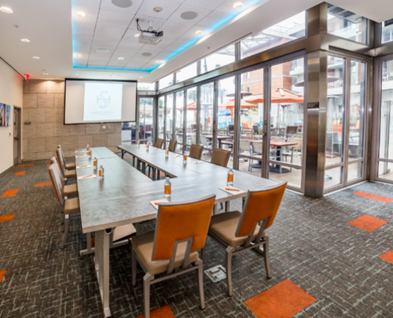 meeting room with long rectangular table with orange changes and big windows