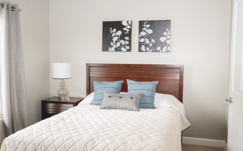 a bedroom with white linens and a wood bed