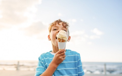 a boy eating ice cream on the beach
