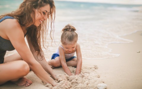 a woman and child playing in the sand