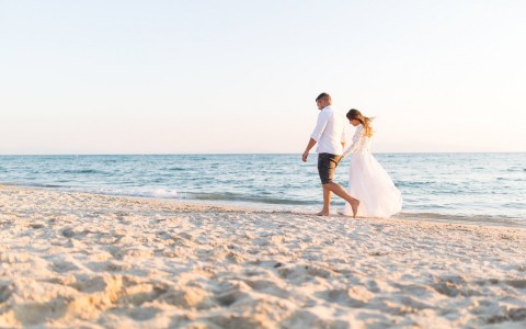 a couple walking on the beach after their wedding