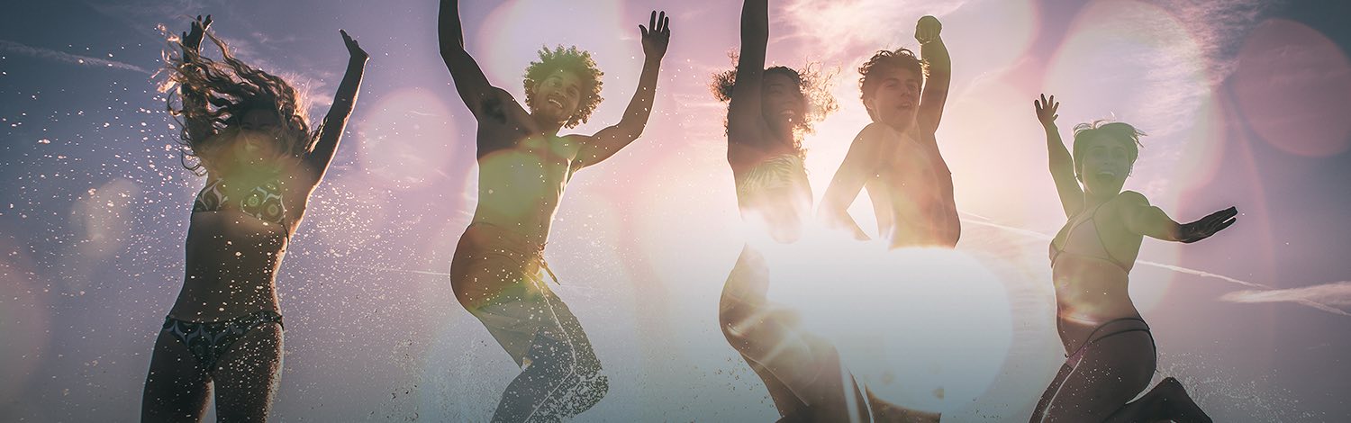 Group of friends jumping with sun shining in the back