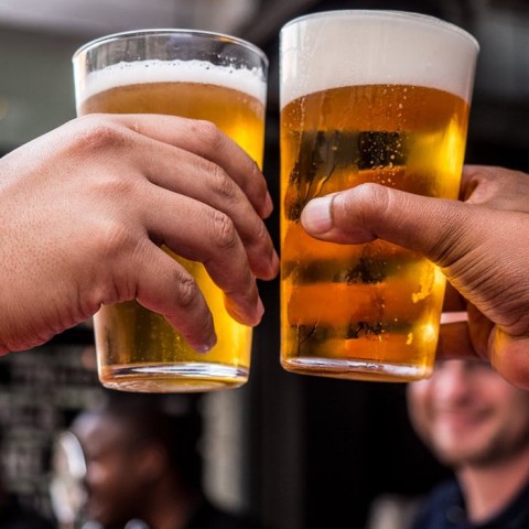 two hands holding up beer glasses to each other