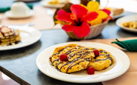 breakfast on a white plate with a floral centerpiece behind