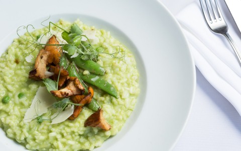 risotto topped with snap peas and chicken served in a white bowl 