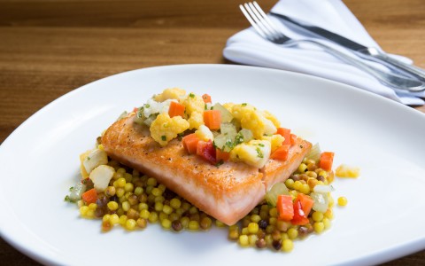 salmon garnished with fresh vegetables on a white plate 