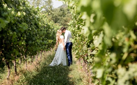 bride and groom smile closely at each other in a vineyard 