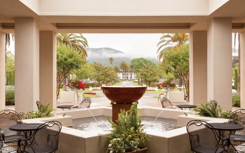 fountain with seating around it with view of mountains in the background 