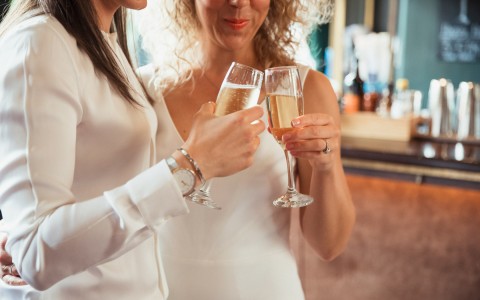 two brides toast with champagne