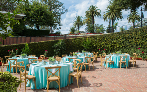 outdoor reception with round tables and wooden chairs