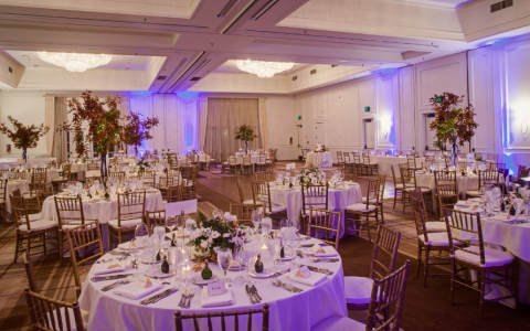indoor ballroom reception with white tablecloths and round tables