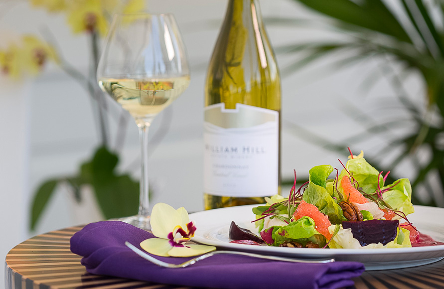 glass and bottle of champagne with a plate of greens