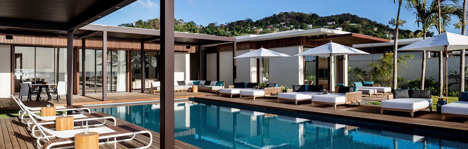 Lounge chairs, cushioned couches, tables, and white umbrellas surround the pool area 