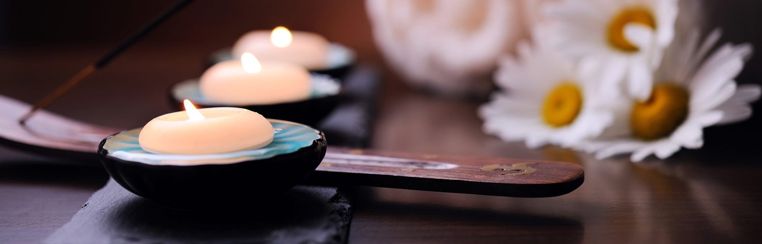 Three small candles lit next to flowers on a table