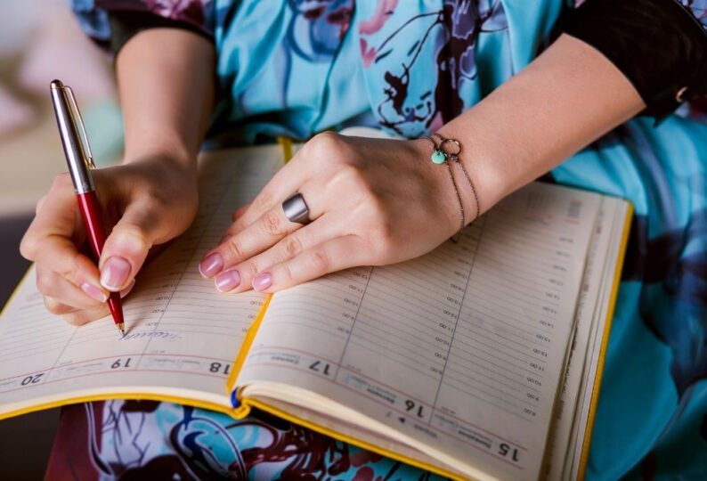 a close view of a woman writing on an agenda