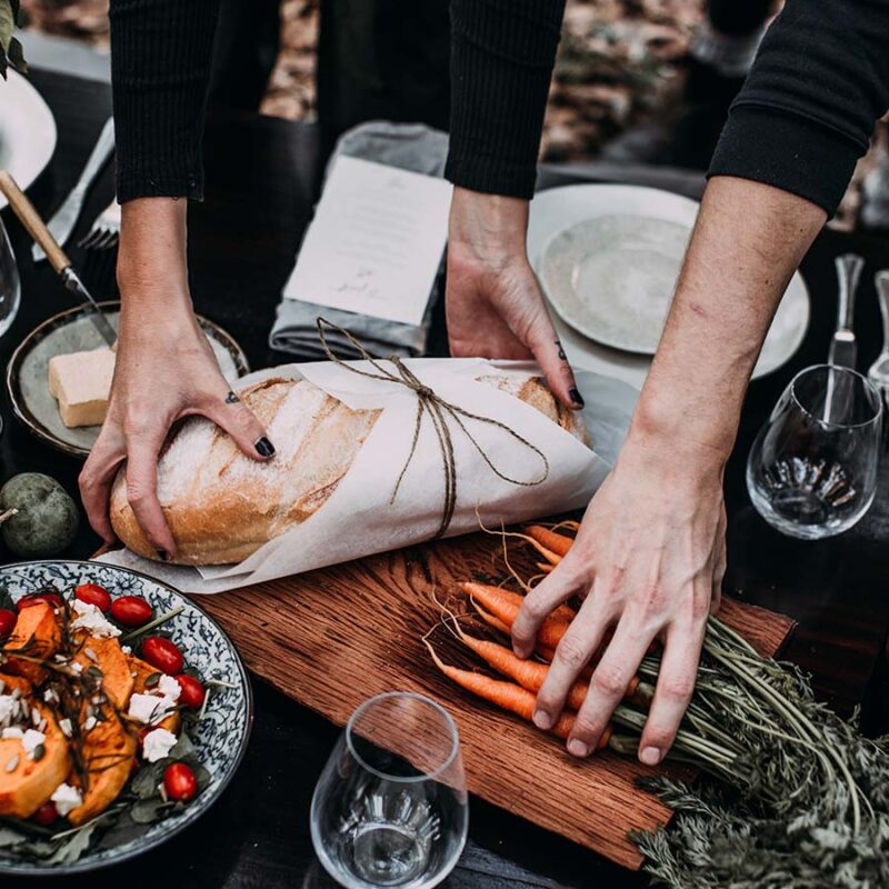 people gathering up around a table with carrots and bread