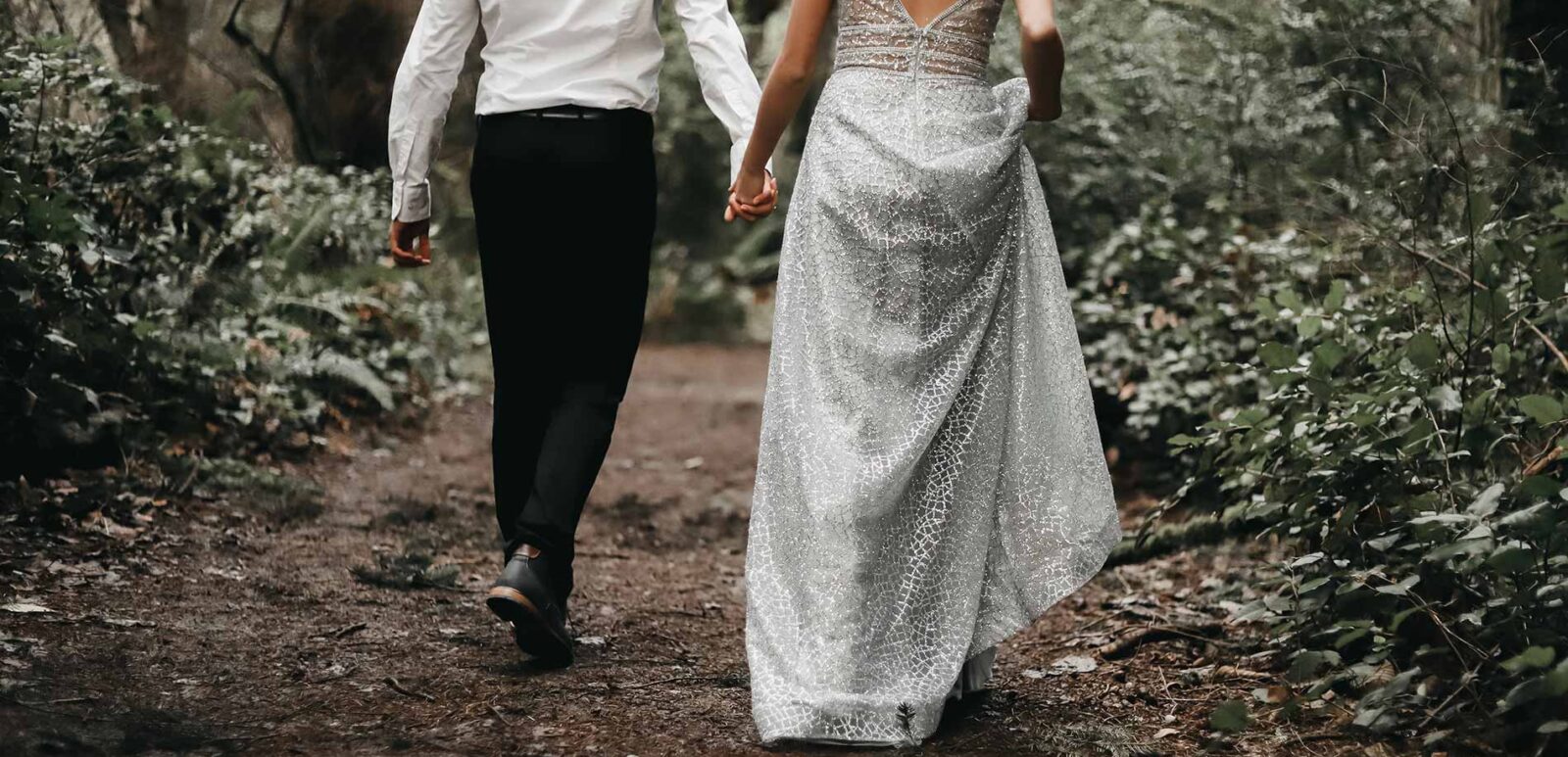 a view of couple walking down a path by the woods