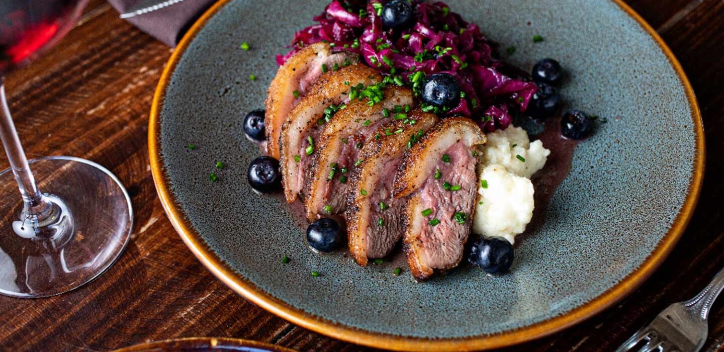 a plate with steak, smashed potatoes and blueberries 