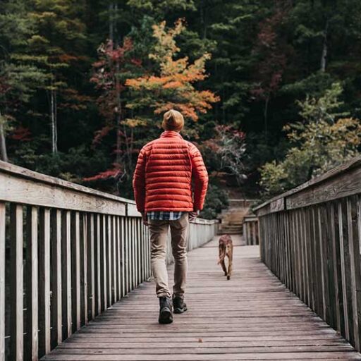 a man walking down a bridge with a dog