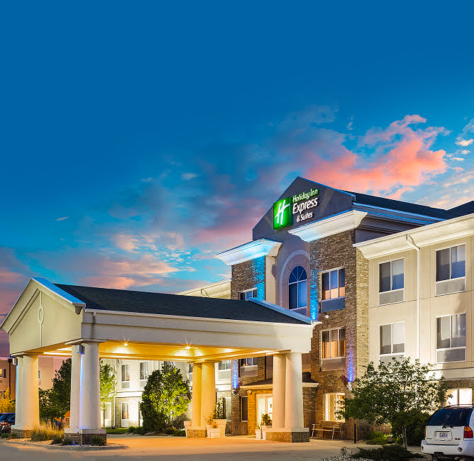 entrance to one of the holiday inn express and suites properties with the sun setting in the back