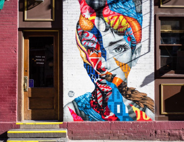 a colorful mural of a woman on a brick building