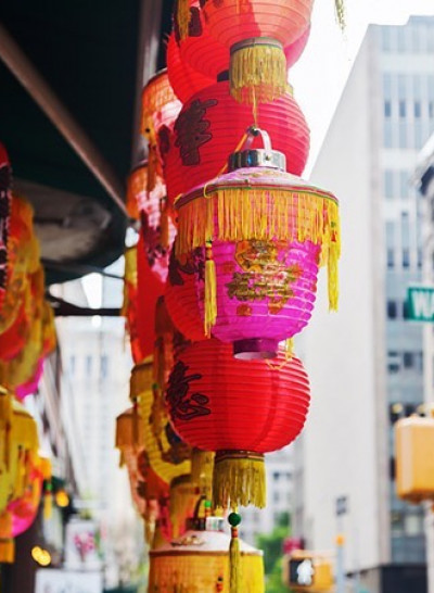 two rows of red chinese lamps handing from an awning on a street