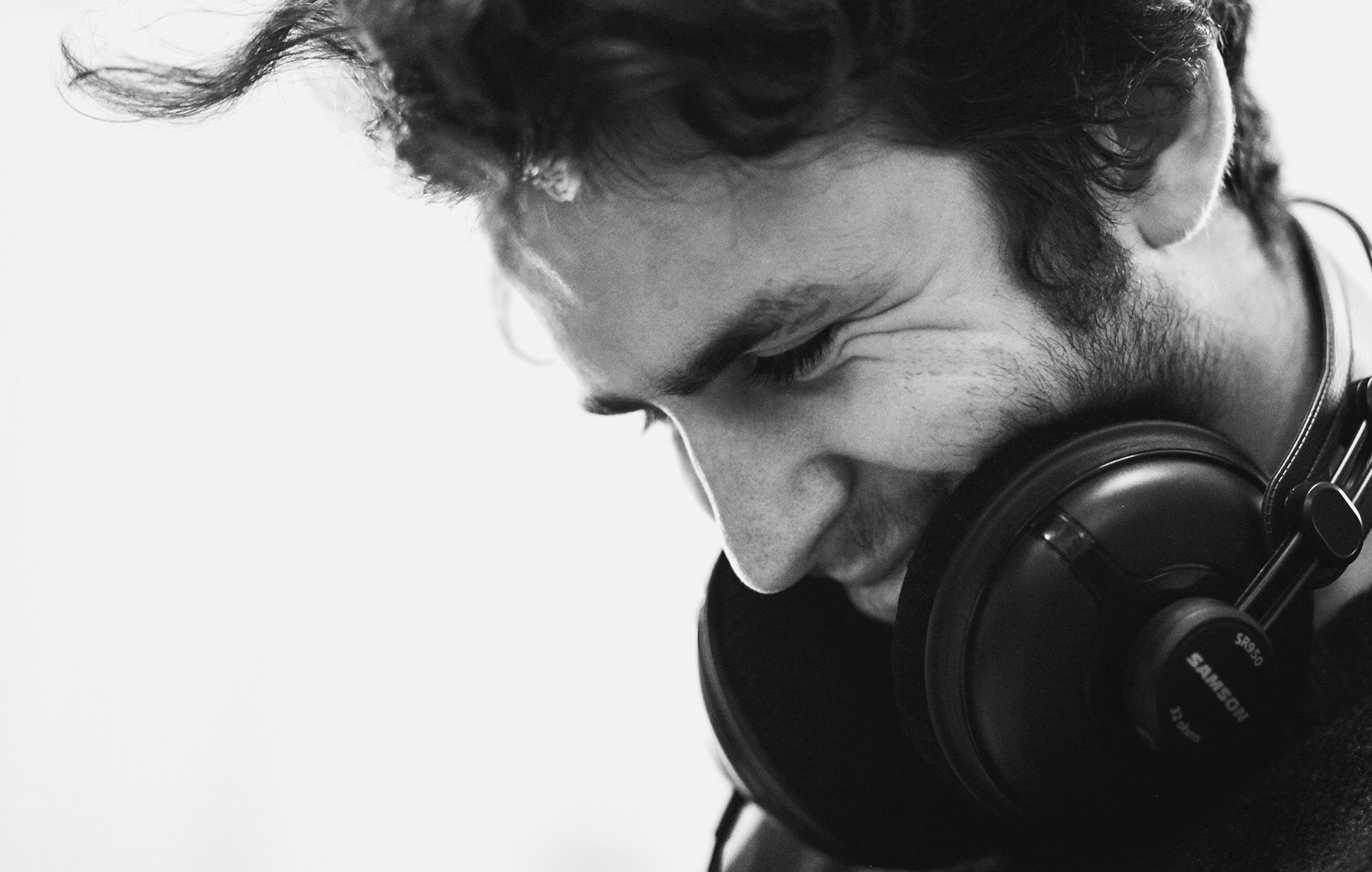 black and white image of a man wearing headphones around his neck looking down