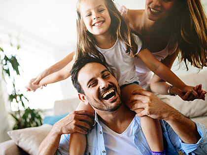 Couple playing with little girl who is on Dad's shoulders