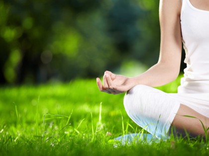 person doing yoga Lotus Pose in grass